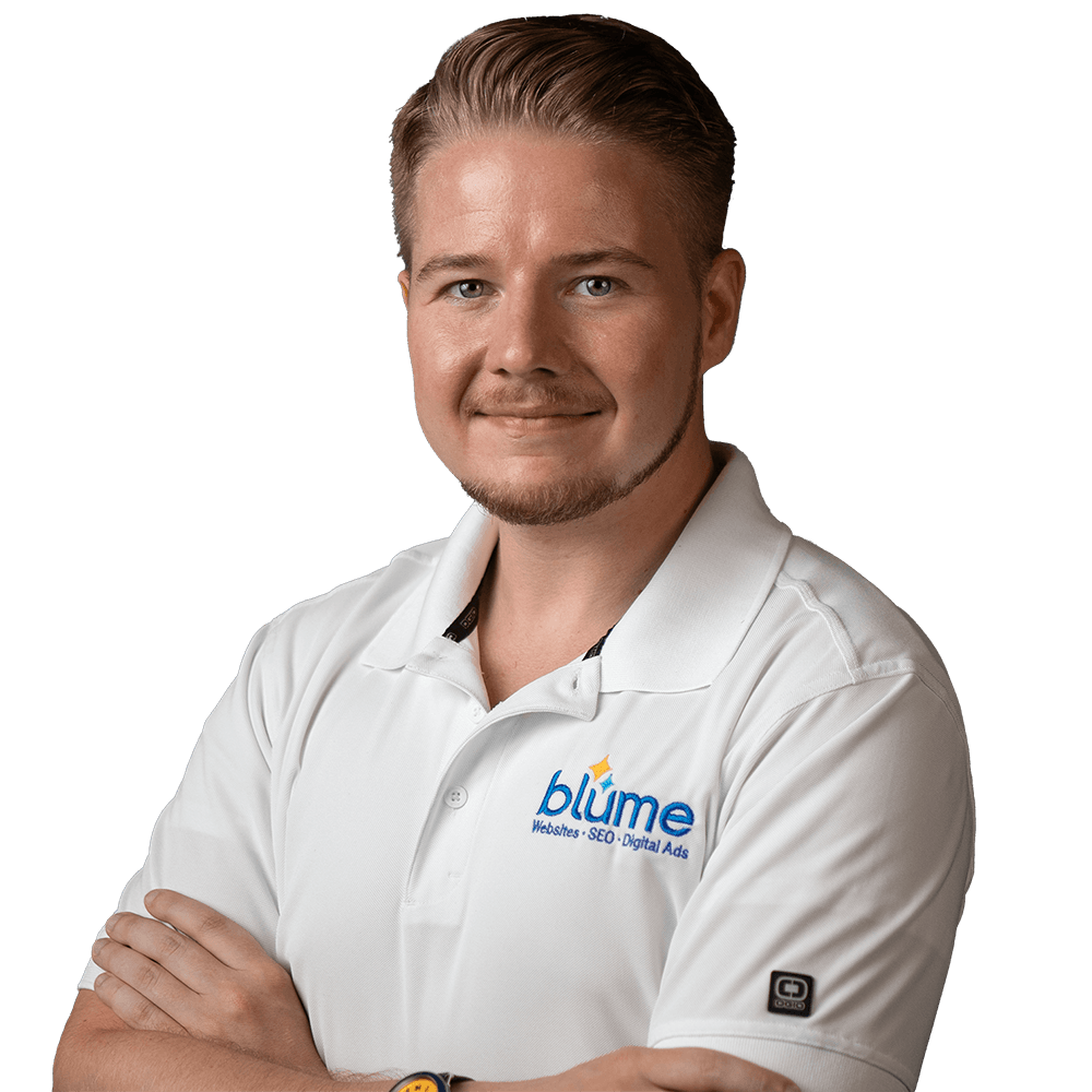A man with short, slicked-back hair and a trimmed beard is standing with arms crossed, wearing a white polo shirt with the "blume" logo and text reading "Websites · SEO · Digital Ads" on the chest.