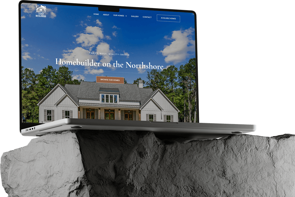A laptop showcasing Website Builds for a homebuilder in Dark Mode, with a house, porch, and trees visible on the screen, rests on a large, rough gray rock.