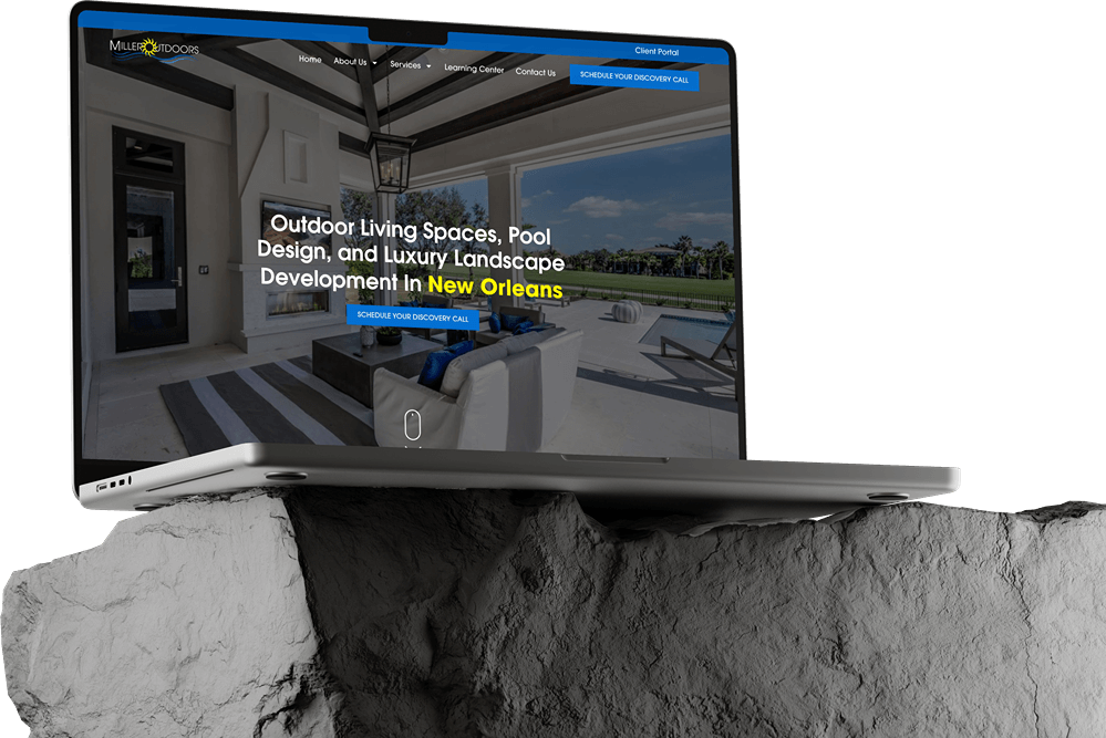 A laptop sits on a grey rock displaying a dark mode website for outdoor living spaces, pool design, and luxury landscape development in New Orleans. The site highlights patio images and showcases expert website builds with a sleek navigation menu.
